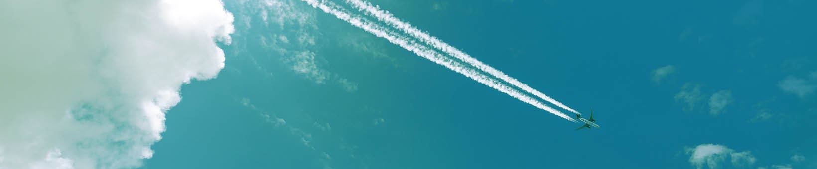 Airliner with contrails flying in a clear blue sky with beautiful cumulus clouds or cumulonimbus. Photography, Full frame.